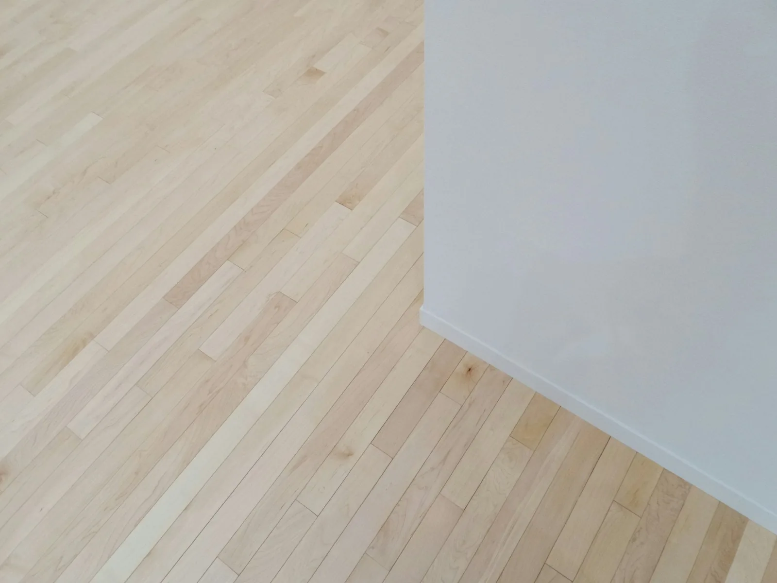 Pale wood floor meeting a plain white wall