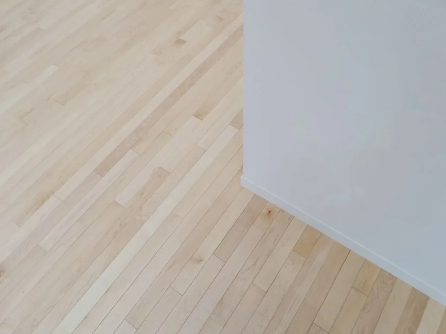 Pale wood floor meeting a plain white wall