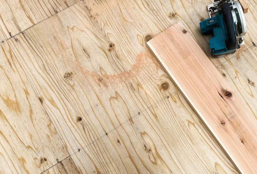 A single board and a saw resting on a bare subfloor