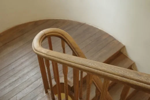 Curved wooden handrail at the top of a stair