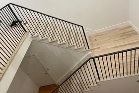 Black steel railing around a light oak stair