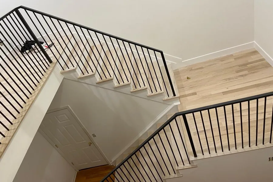 Black steel railing around a light oak stair and landing