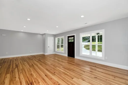 Empty room with a pale oak floor and white trim