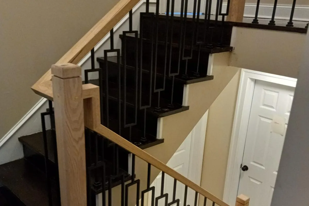 Dark stained stair treads with an oak handrail and black iron balusters
