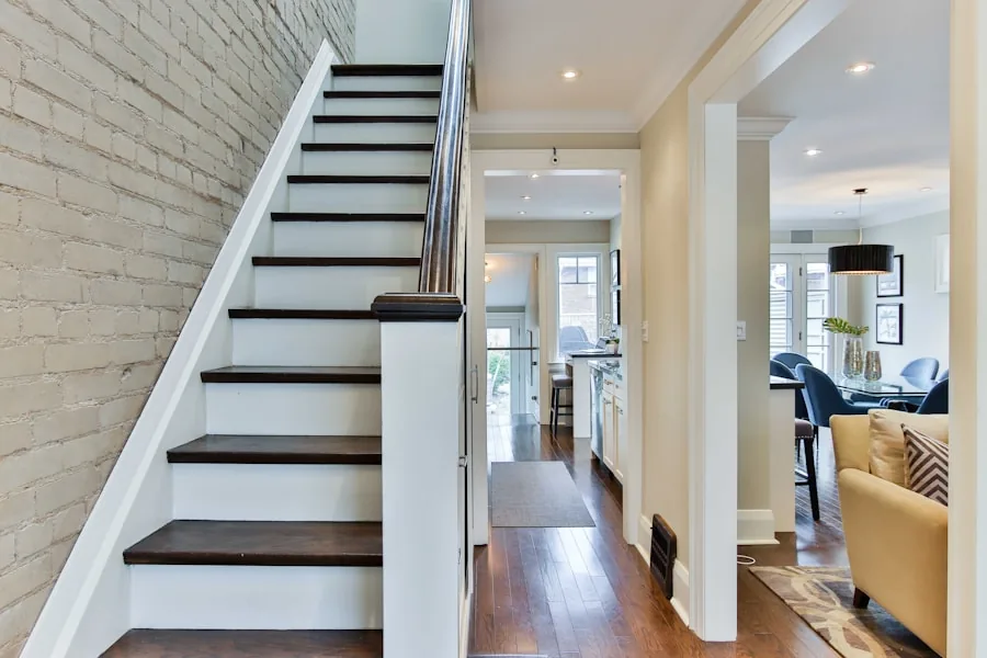 Stair with white risers and dark treads beside an exposed brick wall